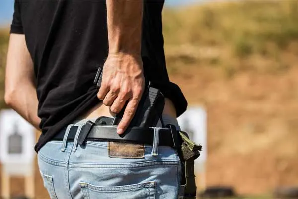 guy taking a black gun out of his back pocket